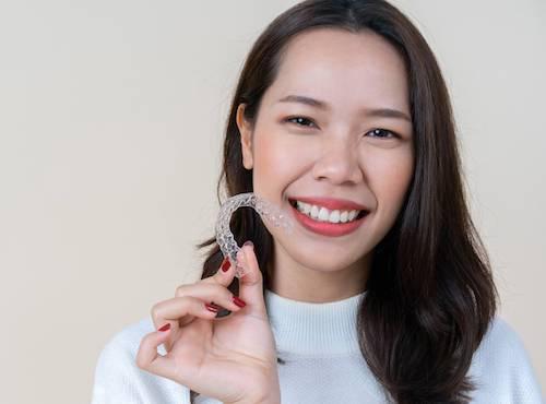 woman holding invisalign clear aligner | sunnyvale ca dentist