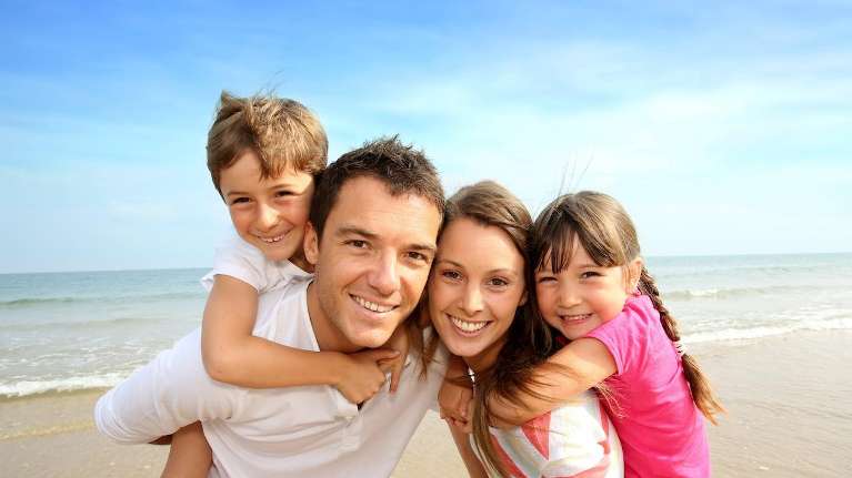 family of four hugging on beach | general dentist sunnyvale ca